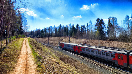 A railway with rails in autumn or spring on a sunny day. Landscape with trees and a slope