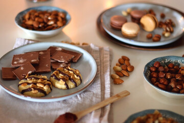 Cup of tea or coffee, cookies, macaroons, chocolate, various nuts and cocoa powder on white background. Selective focus.
