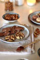 Cup of tea or coffee, cookies, macaroons, chocolate, various nuts and cocoa powder on white background. Selective focus.