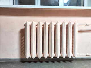A classic radiator sits below a window in a room with pink walls. Vintage Radiator Against Pink...