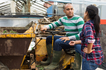 Farm workers have a dialogue next to the tractor