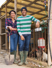 woman; male; man; female; farmers; poultry; farm; work; farming; colleagues; hens; chicken; coop; portrait; shovel; job;..adult; nature; indoors; smiling; smile; scene; labor; activity; net; feathers