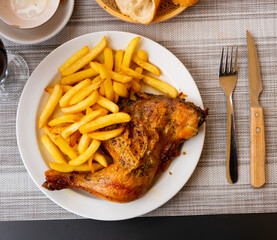 French fries and piece of fried chicken is served on large white platter, completed with beer