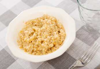 Appetizing milk oatmeal porridge served on plate for breakfast