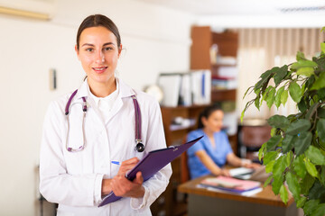 Portrait of positive female doctor wearing uniform standing with stethoscope in modern clinic