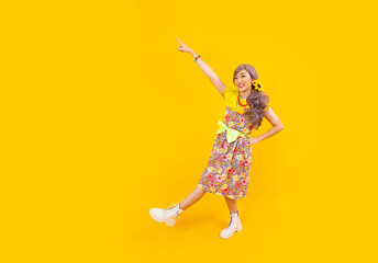 Asian hippie woman dress in 80s vintage fashion with colorful retro clothing while dancing isolated on yellow background for fancy outfit party and pop culture concept