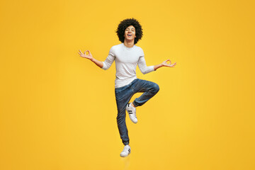 Funny young man sitting in mid air, balancing on one leg