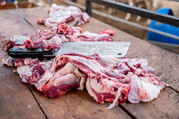 meat chops on wooden cutting board with knife after all work done and ready to be cooked , served,...