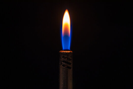 Detalle de la llama encendida de un mechero de gas azul en la oscuridad
