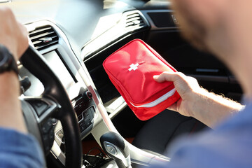 Obraz premium Man with first aid kit inside car, closeup
