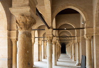 Corridor with arched stone colonnade encircling inner courtyard of Mosque of Uqba in Tunisian city...