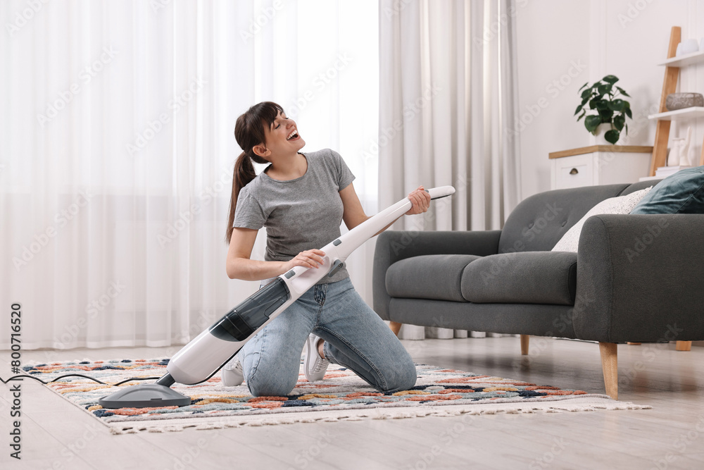 Wall mural Happy young housewife having fun while cleaning at home