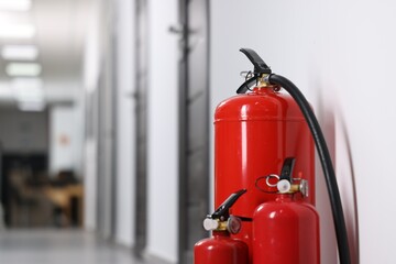 Fire extinguishers in hall, closeup. Space for text