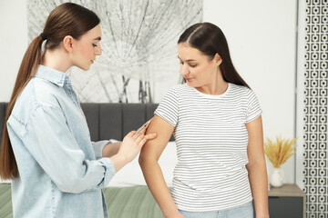 Woman giving insulin injection to her diabetic friend in bedroom
