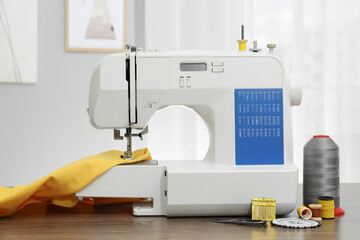 Sewing machine with fabric and craft accessories on wooden table indoors