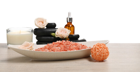 Natural sea salt in bowl and other spa supplies on wooden table against white background