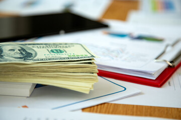 Symbolizing corporate earnings and economic analysis, stack of US dollars rests on business desk...