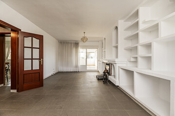 Fireplace of a house with security grill on a wall with white built-in shelves, smooth white walls,...