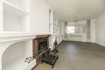 Fireplace of a house with a security grill on a wall with white built-in shelves, smooth white...