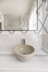 Bathroom c with single sink, not built into marble countertop, decorative paper on the wall and mirror with black metal edge