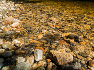 Shallow River With A Bed Of Rocks Highlighted By The Sun