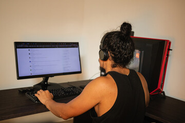 Professional Multimedia Editing Workflow. A young adult works from home as an audiovisual editor, creating content and immersed in an exciting project in front of his computer.