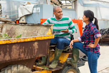 Hispanic male farmer working in a company driving a mini dump truck discusses the current topic of...