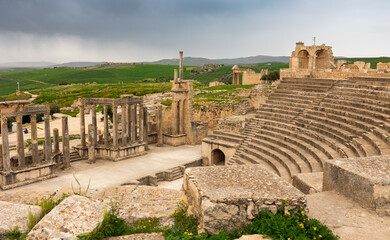 Ruins of Roman theatre in ancient settlement of Dougga in Tunisia with semi-circular orchestra,...