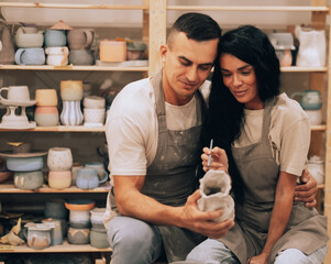 A young smiling couple works in a pottery workshop. Painting a vase. The concept of hobbies