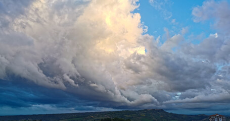 Enorme nuvola bianca sopra il paese in cima alla collina porta la pioggia in una giornata di sole...