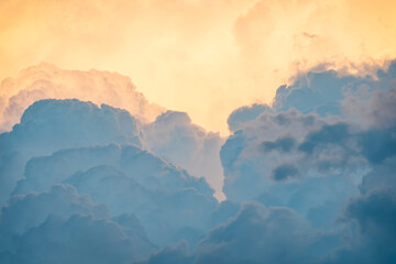 Close-up shot of clouds with different shades of gray and orange reflecting sunlight at sunset. Paradise sky
