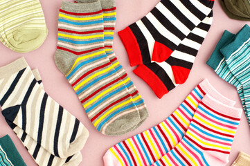 Colorful socks on a pink background. A lot of socks are scattered on the surface. Clothing in the...