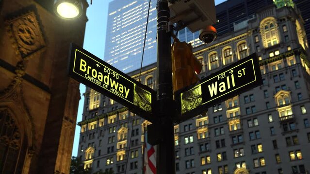 Broadway and Wall Street signs illuminated at dusk in Manhattan, New York