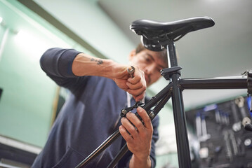 Hispanic man assembling the brake system of a bicycle as part of the maintenance service he...