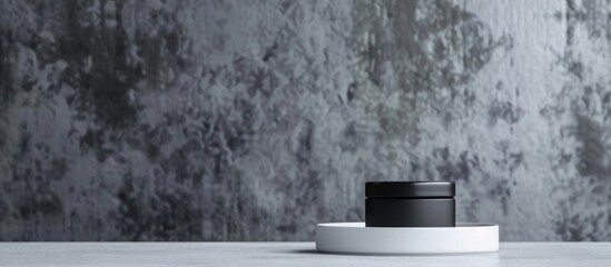 A close up of a black and white container sitting on a white pedestal, creating a simple and elegant aesthetic