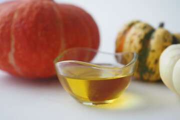 Pumpkin seed oil in glass on white background .