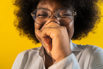 retrato de mujer afrolatina usando lentes y mirando al frente mientras se tapa con su mano su...