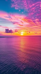 Fototapeta premium Aerial view of a vibrant sunset over the ocean, painting the sky with streaks of orange, purple, and pink