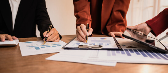 Diverse group of professionals businesswomen gather in meeting room for collaborative discussions on finance, strategy, and teamwork, technology tablets and laptops for data analysis and presentation