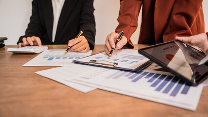 Diverse group of professionals businesswomen gather in meeting room for collaborative discussions on finance, strategy, and teamwork, technology tablets and laptops for data analysis and presentation