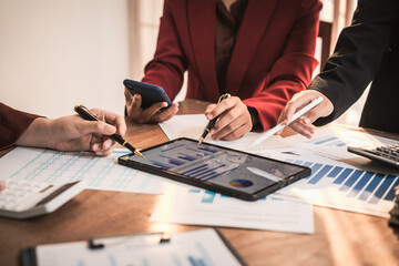 Diverse group of professionals businesswomen gather in meeting room for collaborative discussions on finance, strategy, and teamwork, technology tablets and laptops for data analysis and presentation