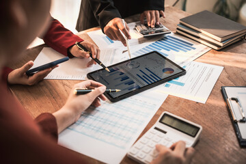 Diverse group of professionals businesswomen gather in meeting room for collaborative discussions on finance, strategy, and teamwork, technology tablets and laptops for data analysis and presentation