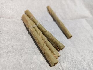 Bidi or Beedi, A beedi is a thin cigarette or mini-cigar filled with tobacco flake and commonly wrapped in a tendu or Piliostigma racemosum leaf tied with a string or adhesive, bidi isolated 