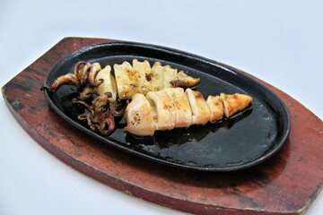 Grilled squids or 'Cumi Bakar' is a sweet and tangy seafood dish that is often sold as street food in Indonesia. It is marinated in sweet soy sauce and a mixture of spices before being grilled. 