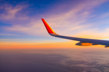 The view from the airplane window to the clouds and sunset. Airplane wing above thick pink and...