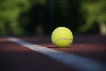 Tennis ball on hard court surface near white line
