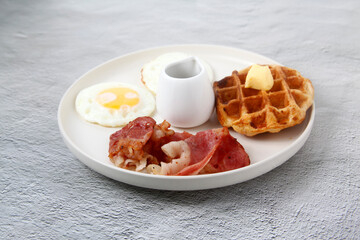 Freshly cooked bacon served with Belgian waffle and egg