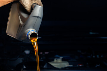 Pour engine oil from the lubricant bottle. Engine background, oil change shop engine service...