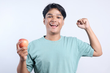 Healthy Strong Young Man Showing Biceps And Apple Fruit on Hands Isolated on White Background. 