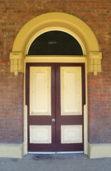 Double doors within an arched entryway surrounded by brick walls